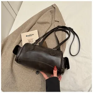 Détail d'un sac rétro en similicuir mat avec poches latérales et boucles métalliques