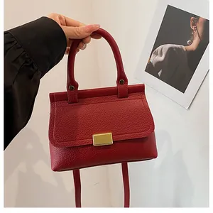Vue détaillée du sac à main en cuir grainé rouge avec un fermoir en métal doré texturé