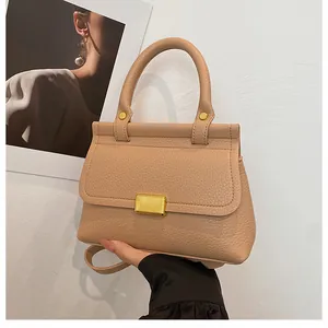Détail du sac à main beige en cuir grainé avec une boucle carrée dorée élégante