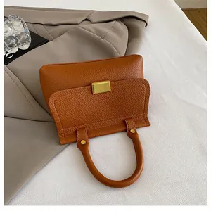Détail du sac à main marron caramel avec texture de cuir litchi et fermoir en métal doré