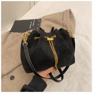Detail of black matte suede bucket bag with gold chain and drawstring closure