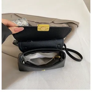Détail du sac noir à motif litchi avec fermoir doré et poche zippée interne