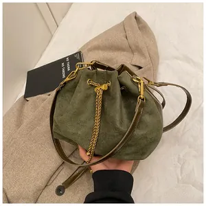 Detail of olive green suede bucket bag with gold chain drawstring and leather strap