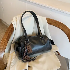 Sac hobo rétro en cuir noir avec breloque chocolat sur une chaise en bois élégante