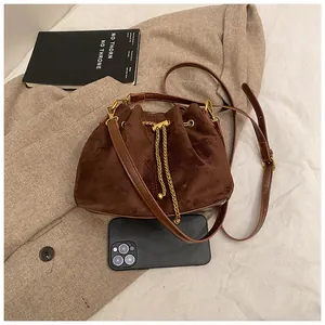 Top view of compact brown suede bucket bag showing internal capacity with a smartphone
