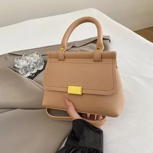 Sac bandoulière élégant en cuir grainé beige avec boucle dorée sur fond de tissu doux