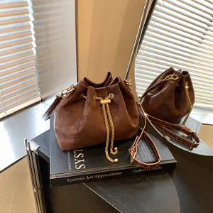 Vintage brown suede bucket bag with gold chain drawstring on an art book background
