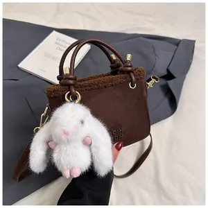 Détail du sac seau en daim marron foncé avec bordure en peluche et breloque lapin mignonne