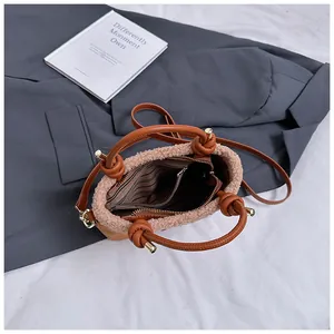 Détail du sac seau en peluche marron montrant la doublure rayée et la poche zippée