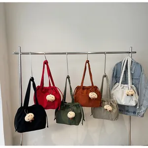 Detail of colorful corduroy tote bags with drawstring closures and alpaca charms
