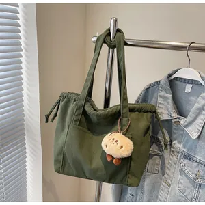Detail of army green corduroy tote bag featuring drawstring closure and plush pendant