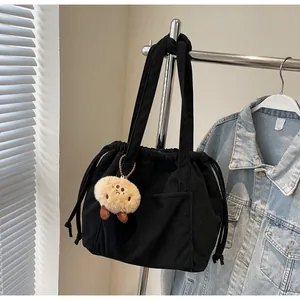 Detail of black corduroy tote bag with drawstring closure and plush clown charm