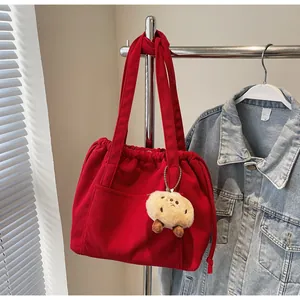Detail of red corduroy tote bag with drawstring closure and cute plush doll charm