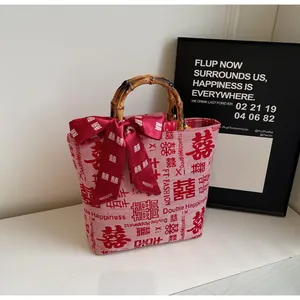 Detailed shot of bamboo handle and red silk scarf on a pink wedding canvas tote bag