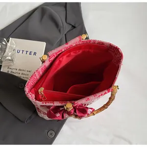 Close-up of red canvas wedding tote with bamboo handles and silk bow decoration