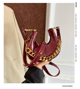 Detailansicht der weinroten Halbmond-Tasche mit glänzendem Leder und goldener Kette