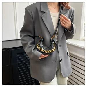 Detail der schwarzen Mini-Tasche in Kroko-Optik mit Goldkette und Schulterriemen