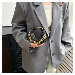 Mini-Sichelhandtasche in glänzendem Schwarz mit goldener Gliederkette am Model