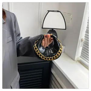 Detail der schwarzen Mini-Halbmondtasche aus Leder mit grober goldener Kette