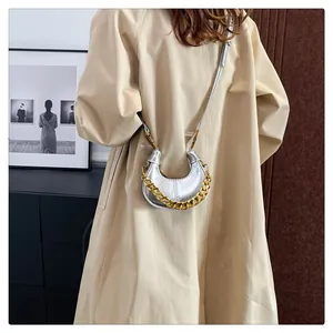 Details einer silbernen halbmondförmigen Tasche mit Metallic-Falten und goldener Kette