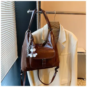 Details der braunen Hobo-Tasche mit Schnallentasche und weißem Hundeanhänger im Vintage-Stil