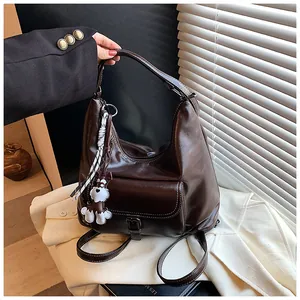 Detail der braunen Vintage-Einkaufstasche mit glänzendem Leder und Hunde-Schlüsselanhänger