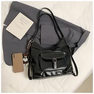 Detailansicht der schwarzen PU-Ledertasche mit Metallschnalle und süßem Hundeanhänger