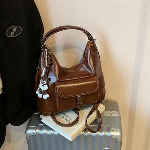 Braune Vintage Hobo-Tasche aus Kunstleder mit weißen Nähten und Hundeanhänger auf Koffer