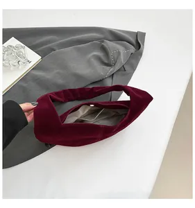 Detail view of the burgundy velvet bag showing metal magnetic closure and gray inner lining
