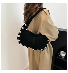 Detail of black matte suede shoulder bag with silver rivet studs on khaki trench coat