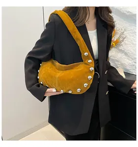 Detail of mustard yellow suede hobo bag featuring large silver stud accents and strap