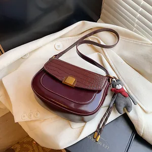Sacoche selle bordeaux à relief crocodile avec boucle dorée et breloque ourson