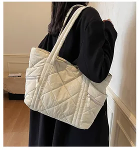 Detail view of cream quilted tote bag showing large diamond stitching and side zipper pocket