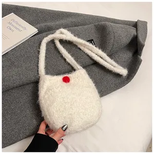 Détail du petit sac bandoulière en fausse fourrure blanche avec pompon rouge