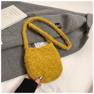 Détail de la texture d'un sac bandoulière en peluche jaune sur fond de manteau gris