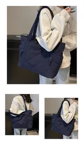 Detail of dark blue quilted tote bag showing rhombus pattern and side zipper pockets