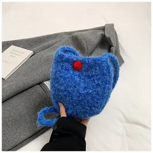 Vue détaillée du sac à bandoulière en tricot bleu roi avec pompons rouges vifs