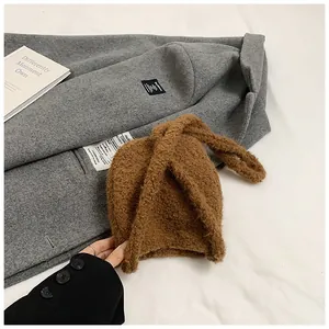 Détail montrant la texture épaisse d'un sac seau en peluche marron caramel sur manteau
