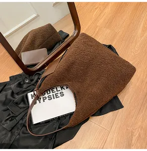 Dettaglio borsa hobo in peluche marrone scuro con tracolla su abiti invernali chic