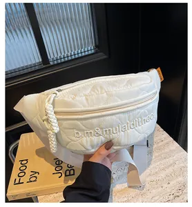 Detail of white quilted nylon chest bag showing diamond stitching and letter embroidery