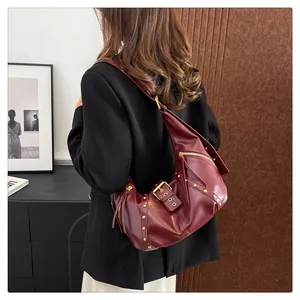 Detail of dark red crescent bag featuring gold rivets and vintage leather texture