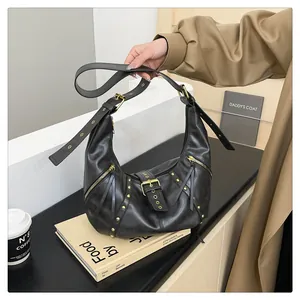 Detail of vintage black leather crescent bag with adjustable straps and gold metal studs