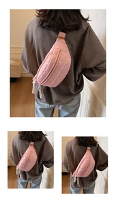 Close-up of pink quilted nylon chest bag with embroidered letters and zipper detail