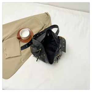 Detail view of black vintage oil wax leather shoulder bag with gold rivets and wide strap