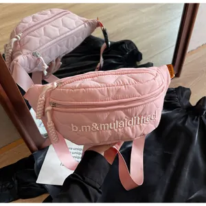 Detail of pink quilted crossbody bag with heart patterns and embroidered lettering