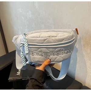 Detail of light blue quilted chest bag with heart embroidery and adjustable strap