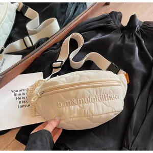 Detailed macro view of cream quilted nylon chest bag featuring embroidered lettering