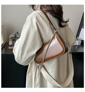 Détail d'un sac demi-lune en cuir marron brillant avec une chaîne en métal argenté chic