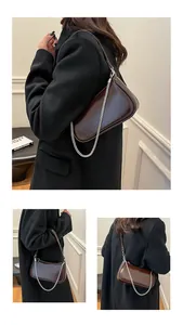 Détail de la texture cuir brillant et de la chaîne argentée sur sac marron foncé