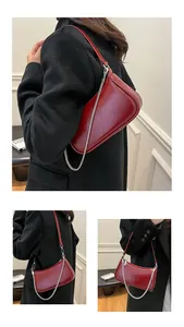 Vue détaillée du cuir huilé rouge brillant et de la bandoulière en chaîne argentée